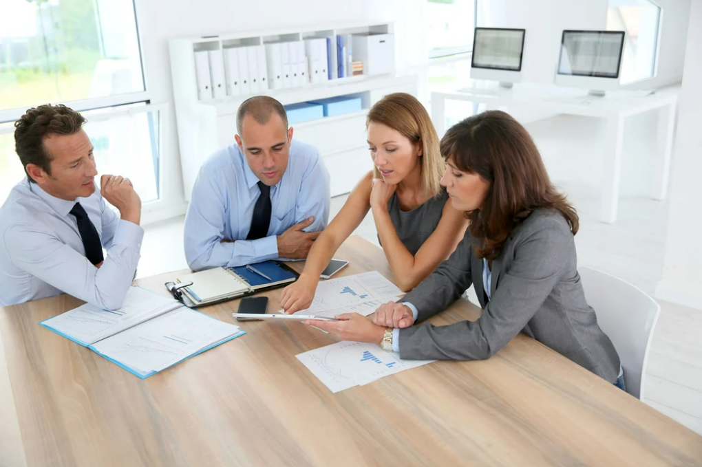 A group of professionals sitting around a table analyzing datasets representing Analyze U, an add-on for the top labor union app, UnionWare.