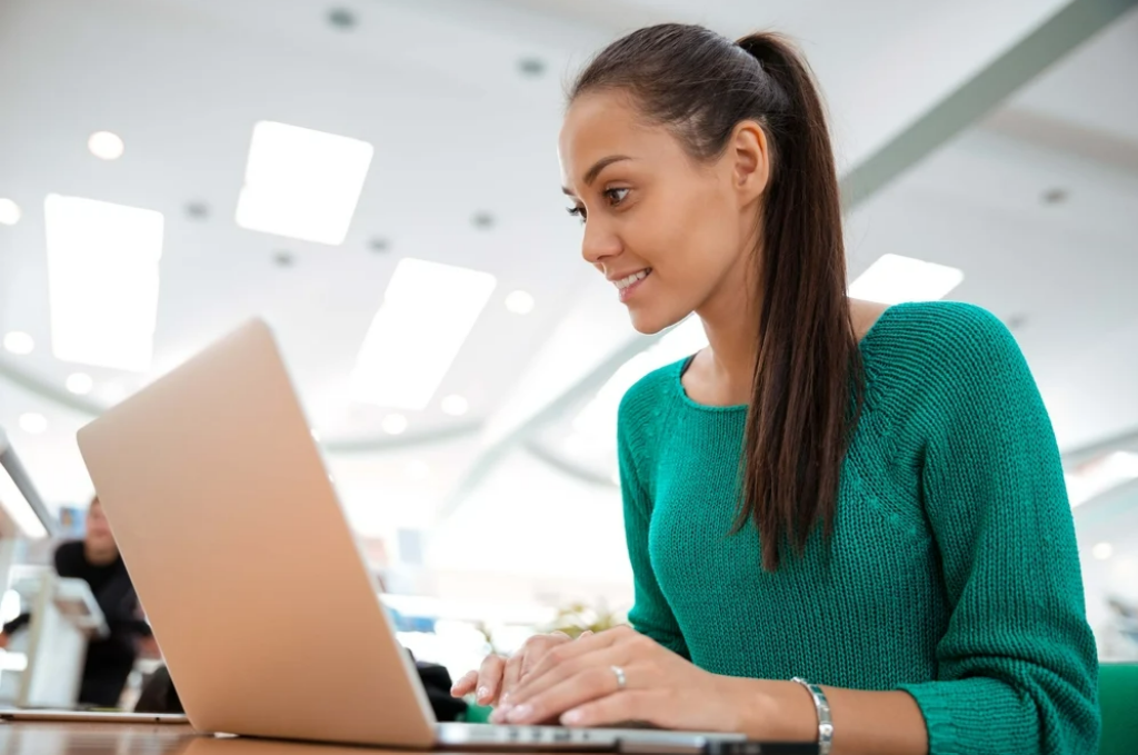 A happy woman working on a laptop, demonstrating UnionWare’s effectiveness as a top labor union app.